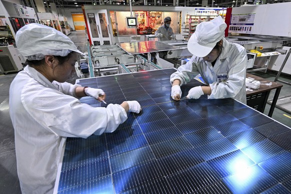 Workers work on solar panels at a production factory in Sihong county in east China&#039;s Jiangsu province on Jan. 23, 2025. (Chinatopix Via AP)