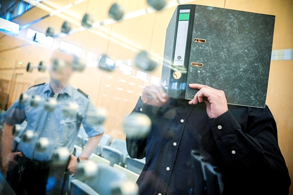 epa07816229 Defendant Nils D. hides his face as he arrives in a courtroom of the higher regional court in Duesseldorf, Germany, 04 September 2019. The Office of the Attorney General of Switzerland acc ...