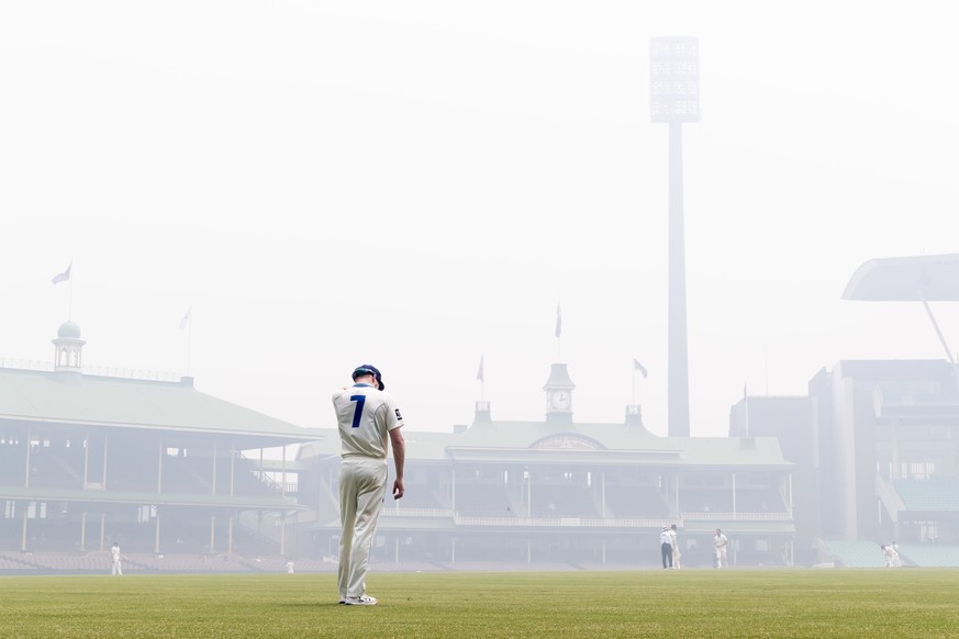 epa08058574 Liam Hatcher of the New South Wales stands in the outfield as bushfire haze covers the piitch day during day three of the Sheffield Shield cricket match between New South Wales and Queensl ...