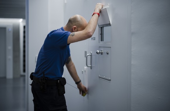BITTE BEACHTEN SIE DIE SPERRFRIST BIS 30. 03. 2022,17:30 --- Ein Aufseher schaut durch das Fenster einer Zellentuer einer Zelle im Gang eines Zellentrakts im Polizei- und Justizzentrum Zuerich (PJZ),  ...