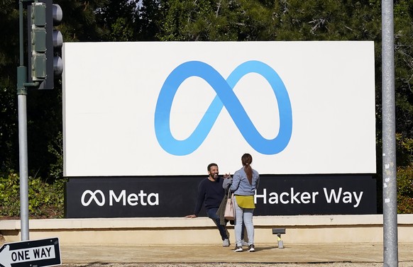 People talk near a Meta sign outside of the company&#039;s headquarters in Menlo Park, Calif., Tuesday, March 7, 2023. Facebook?s parent Meta will slash another 10,000 jobs and will not fill 5,000 ope ...