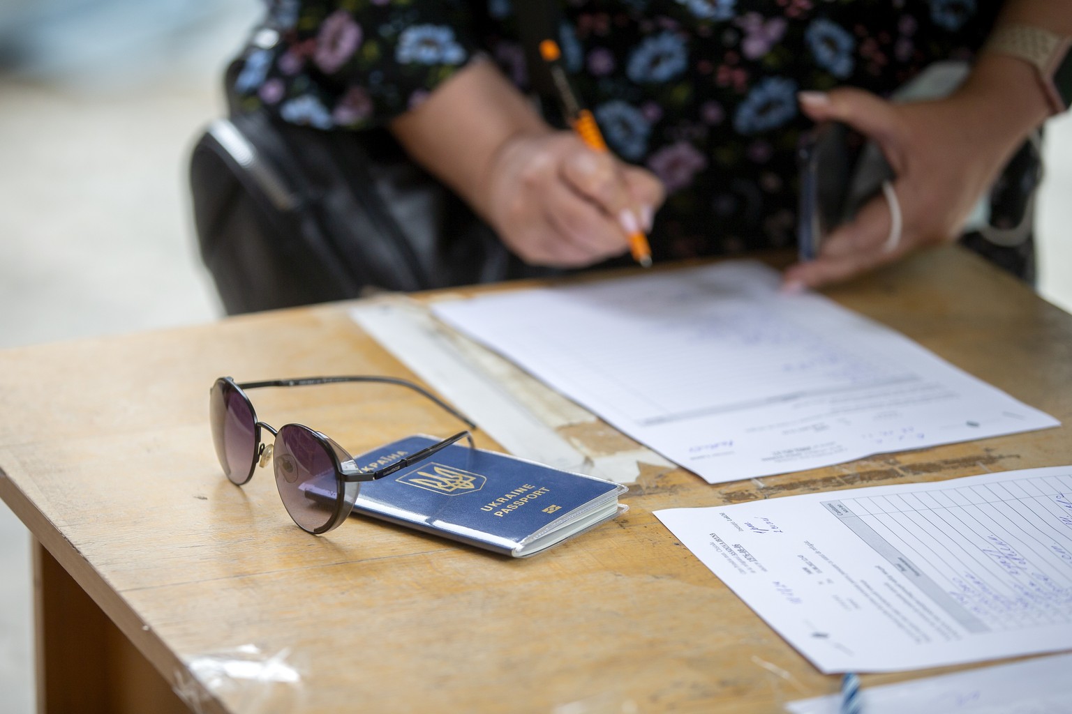 epa10122236 A Ukrainian passport placed on a table as Ukrainian people arrive at a refugee camp set up at the Patria-Lukoil center in Chisinau, Moldova, 15 August 2022. According to data released by t ...