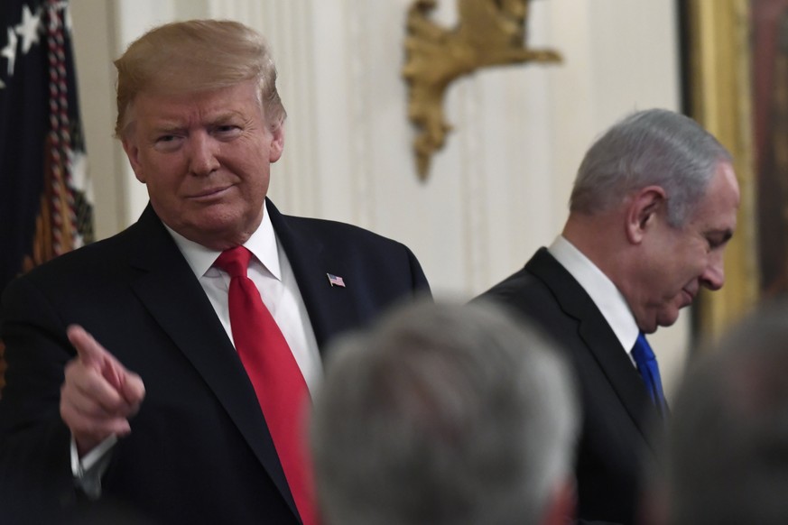 President Donald Trump, left, points to the audience as he stands with Israeli Prime Minister Benjamin Netanyahu, right, during an event in the East Room of the White House in Washington, Tuesday, Jan ...