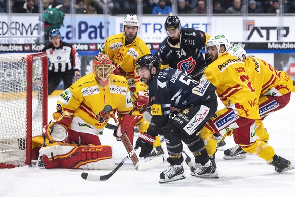 Le gardien biennois Jonas Hiller, gauche, lutte pour le puck avec l&#039;attaquant fribourgeois David Desharnais, centre, et l&#039;attaquant biennois Jason Fuchs, droite, lors de la rencontre du cham ...