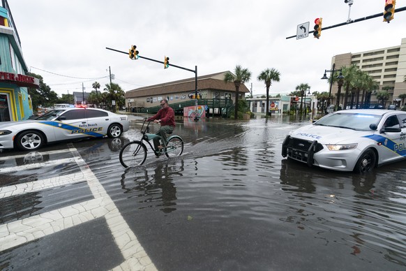 A bicyclist rides through the standing water as law enforcement blocks the intersection to traffic, during the effects from Hurricane Ian, Friday, Sept. 30, 2022, in Folly Island, S.C. (AP Photo/Alex  ...
