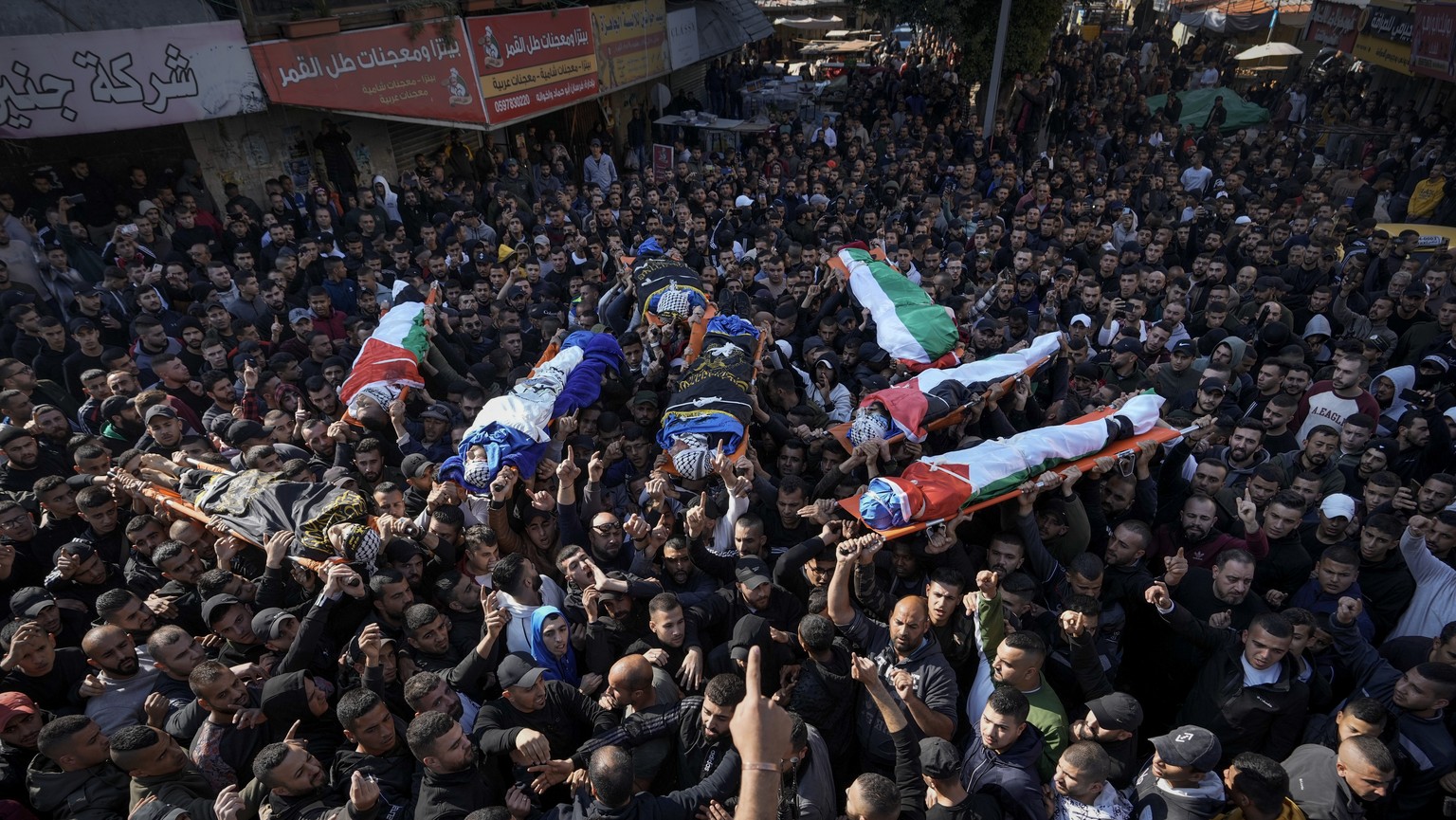 Mourners carry the bodies of eight Palestinians, some draped in the flag of the Islamic Jihad militant group, during a joint funeral in the West Bank city of Jenin, Thursday, Jan. 26, 2023. Israeli fo ...