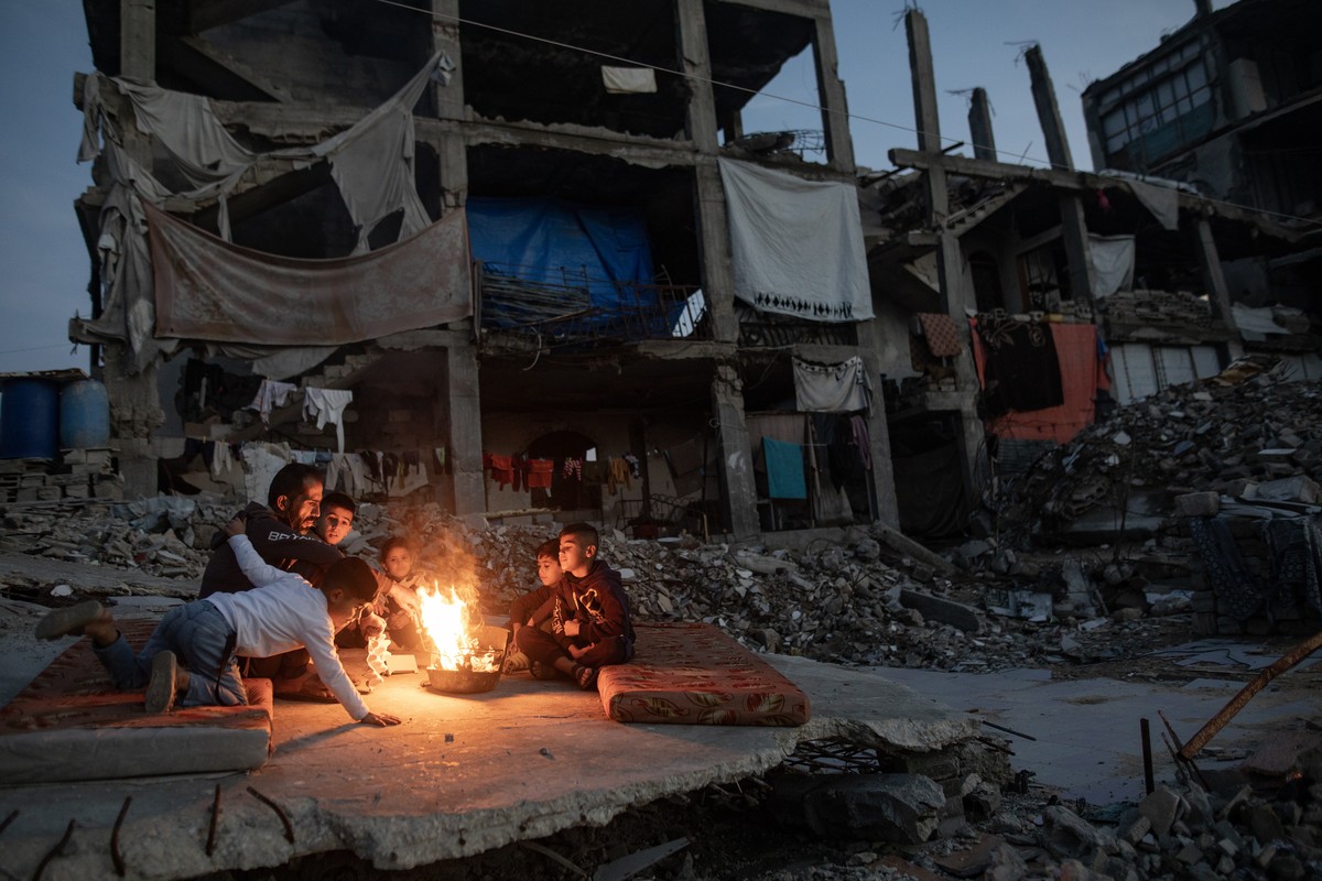 epa12618098 Displaced Palestinians warm themselves near a fire among the ruins of their destroyed home in Khan Yunis, southern Gaza Strip, 30 December 2025, amid a ceasefire between Israel and Hamas.  ...