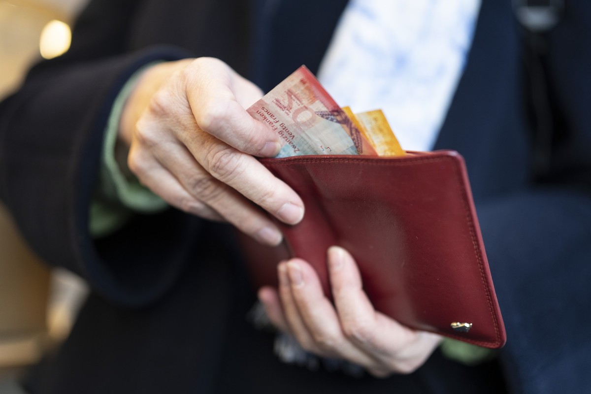 Eine Person zieht waehrend eines Marktes auf dem Hevetiaplatz in Zuerich Schweizer Banknoten aus ihrem Portemonnaie, fotografiert am Freitag, 16. Februar 2024. (KEYSTONE/Gaetan Bally)