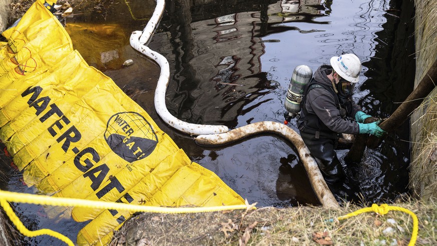 A HEPACO employee works in a creek along Sumner Street in downtown East Palestine, Ohio, on Sunday, February 5, 2023.  A smoldering jumble of dozens of derailed freight wagons carrying dangerous ma...