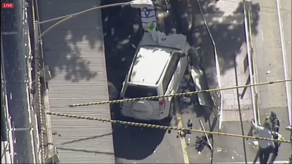 In this photo made video from the Australian Broadcasting Corp., a white SUV vehicle is stopped after allegedly striking pedestrians, Thursday, Dec. 21, 20217, in Melbourne, Australia. Local media say ...