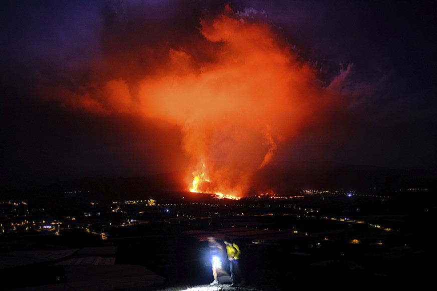 Two people walk as lava spews from a volcano on the Canary island of La Palma, Spain in the early hours of Saturday Sept. 25, 2021. A volcano in Spain's Canary Islands is keeping nerves on edge severa ...