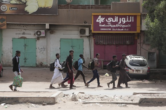 People walk past shuttered shops in Khartoum, Sudan, Monday, April 17, 2023. Sudan's embattled capital has woken up after a third day of heavy fighting between the army and a powerful rival force for…