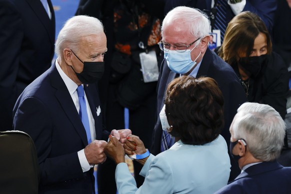 President Joe Biden fist bumps Rep. Maxine Waters, D-Calif., as Sen. Bernie Sanders, I-Vt., looks on, after Biden addressed a joint session of Congress, Wednesday, April 28, 2021, in the House Chamber ...