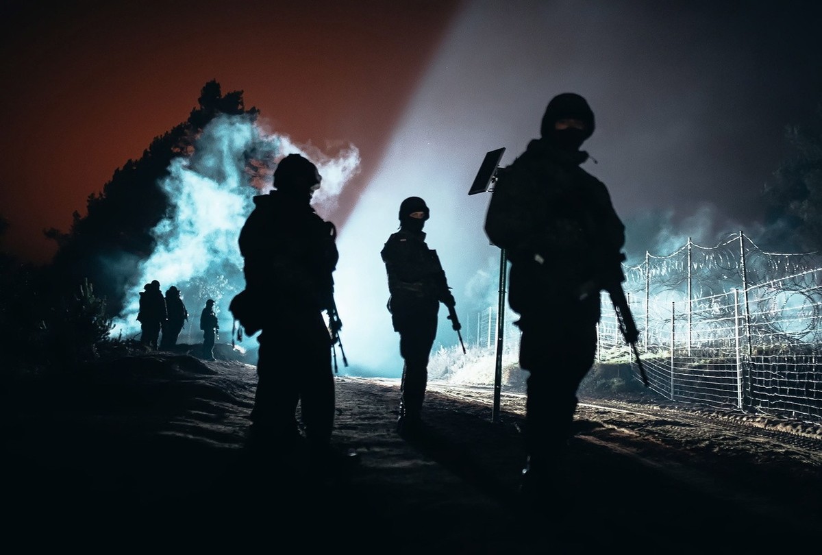 epa09578275 A handout photo made available by Polish Territorial Defence Force shows Polish soldiers guard the fence during 'Operation Strong Support' near the Polish-Belarusian border cross ...