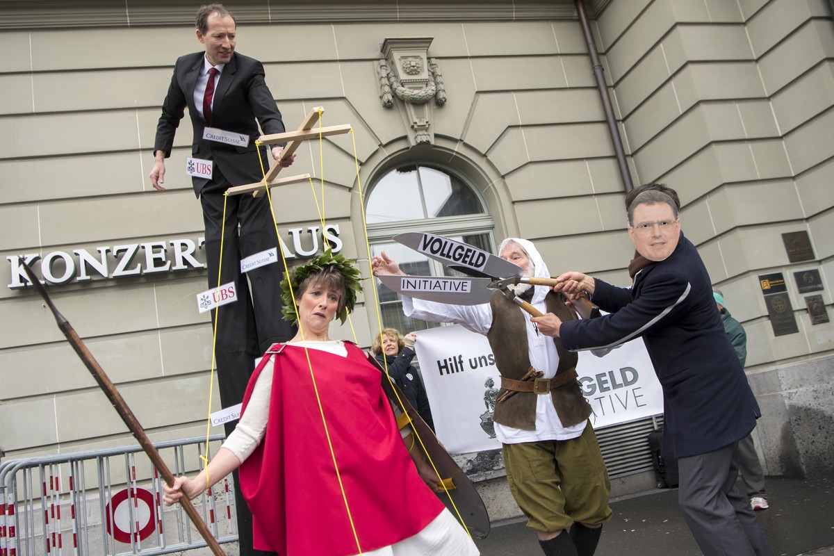 Aktivisten des Komitees "Vollgeld-Initiative" protestieren mit einer Marionetten-Helvetia, Mitte, und einer Maske von SNB Praesident Thomas Jordan, rechts, vor der 109. SNB Generalversammlun ...