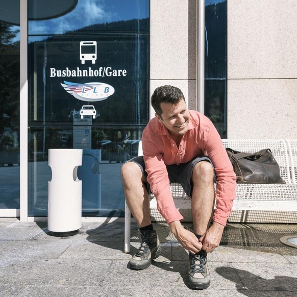 Writer Rolf Hermann ties his shoe laces at the bus terminal in Leukerbad before a hike from Leukerbad via the eight Albinenleitern (Albinen ladders) to Albinen, in the canton of Valais, Switzerland, o ...