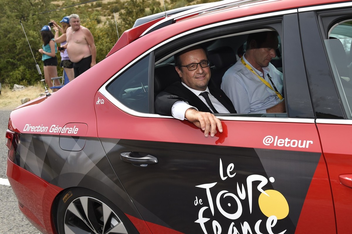 French President Francois Hollande rides in Tour de France director Christian Prudhomme's car during the fourteenth stage of the Tour de France cycling race over 178.5 kilometers (110.9 miles) wi ...