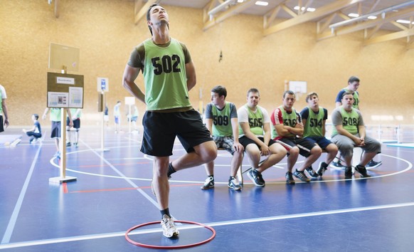 Young men at one of five exercises of the sports exam, here they have to stand in a hoop on one leg with their hands behind their backs, then after ten seconds, they have to close their eyes, and afte ...