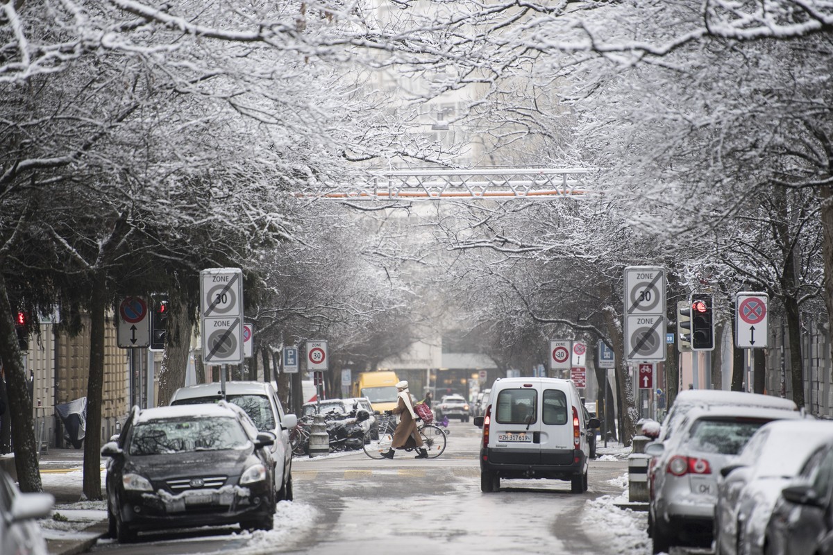 Eine Frau mit Rad ueberquert die verschneite Strasse, am Dienstag, 3. Januar 2017, in Zuerich. In der Nacht auf Dienstag ist der lang ersehnte erste Schnee im Flachland gefallen. Nach Angaben der Wett ...
