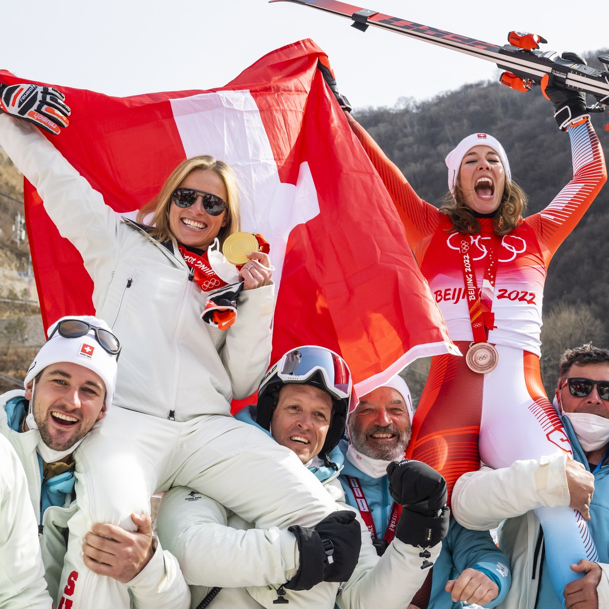 epa09745799 Gold medalist Lara Gut-Behrami (L) of Switzerland and bronze medalist Michelle Gisin of Switzerland celebrate with members of the Swiss team after the victory ceremony of the Women's  ...