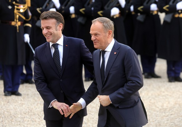 epa11902976 French President Emmanuel Macron (L) welcomes Polish Prime Minister Donald Tusk (R) ahead of a meeting on war in Ukraine and European security at the Elysee Palace in Paris, France, 17 Feb ...