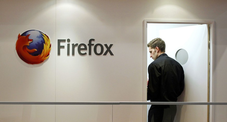 A man is seen next to a Firefox logo at a Mozilla stand during the Mobile World Congress in Barcelona, in this February 28, 2013 file picture. A paper released by the mobile industry&#039;s GSM Associ ...