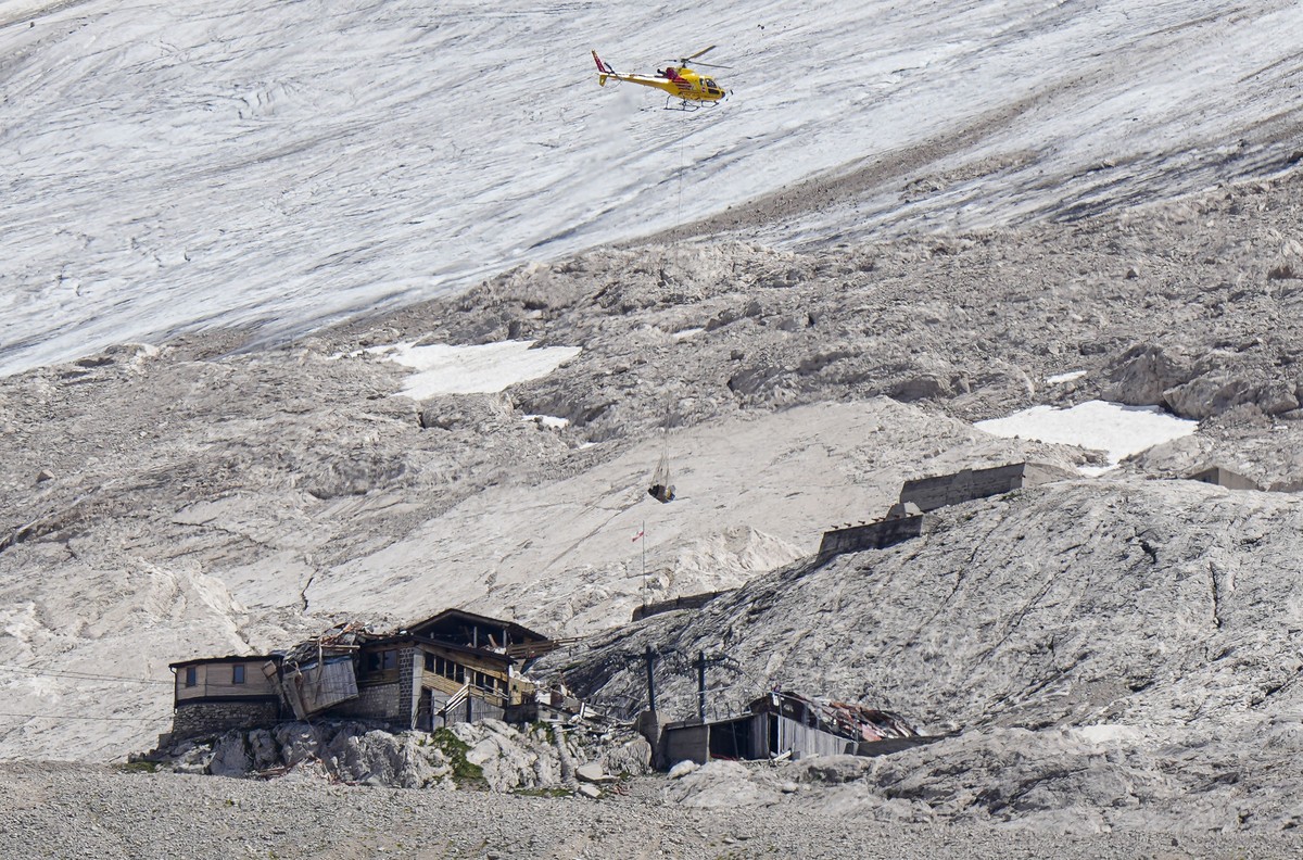 A rescue helicopter carries technical equipment on the Punta Rocca glacier near Canazei, in the Italian Alps in northern Italy, Tuesday, July 5, 2022, where an avalanche broke loose on Sunday, sending ...