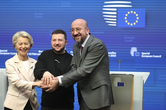 From the left, the President of the European Commission, Ursula von der Leyen, the President of Ukraine, Volodymyr Zelenskyy, in the middle, and the President of the European Council, Charles Michel, join hands after a media conference...