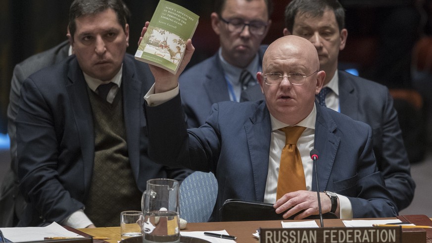 Russian Ambassador to the United Nations Vassily Nebenzia holds up a copy of &quot;Alice&#039;s Adventures in Wonderland&quot; as he speaks during a Security Council meeting on the situation between B ...