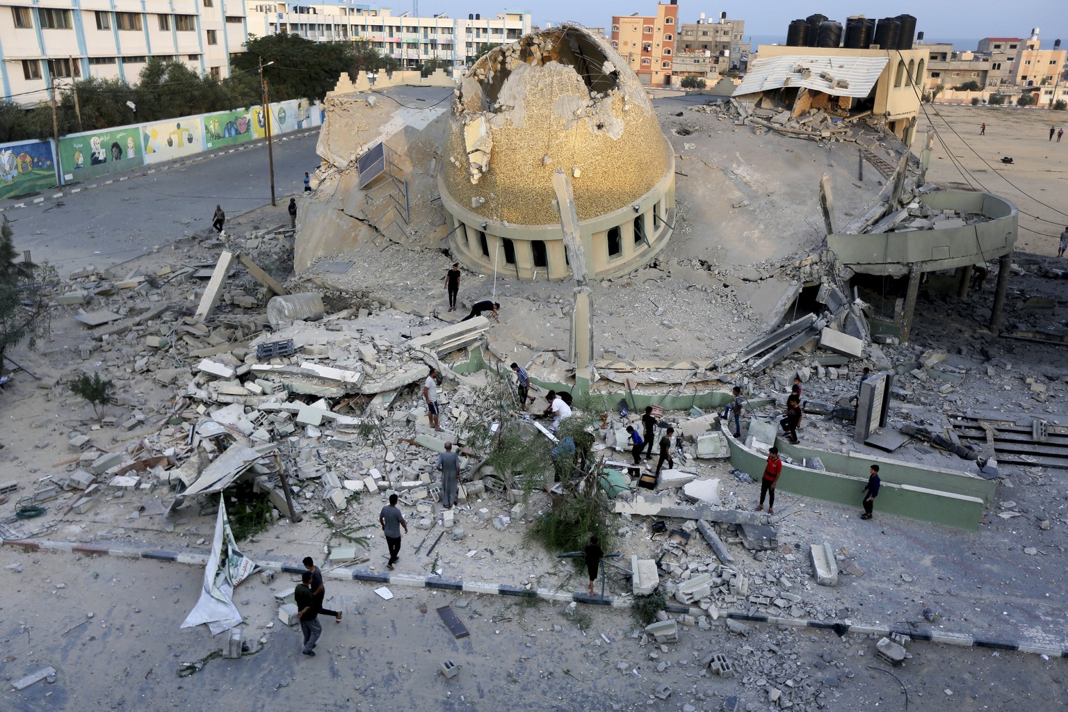 People stand outside a mosque destroyed during an Israeli airstrike in Khan Younis, Gaza Strip, Sunday, October 8, 2023. The Hamas militants broke out of the blockaded Gaza Strip and rampaged through nearby…