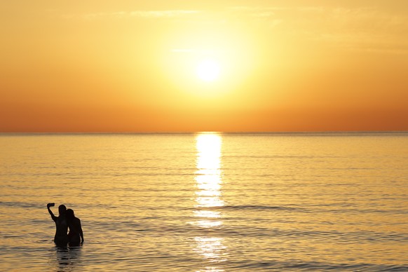 epa13060122 Revelers take a selfie at sunrise while bathing in the sea at Malvarrosa Beach after the Night of San Juan celebrations in Valencia, Spain, 24 June 2026. To welcome the summer solstice, Sp ...