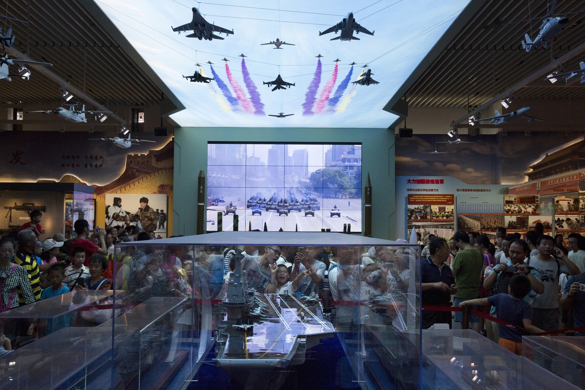 Visitors look at a scale model of a Chinese aircraft carrier during an exhibition to mark the 90th anniversary of the founding of the People's Liberation Army at the military museum in Beijing, C ...