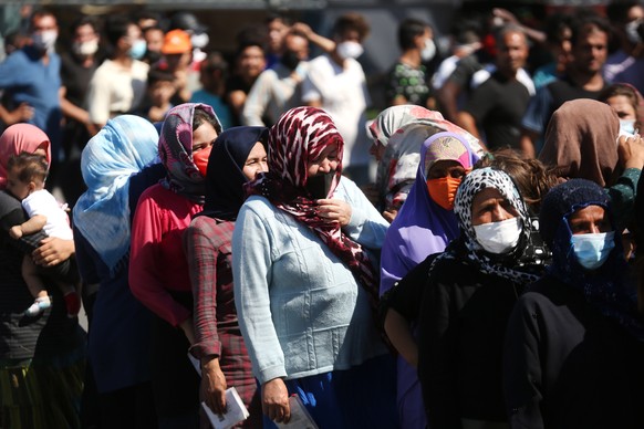 epa08658915 Asylum seekers wait for food, fruits and water near the Moria refugees camp on the island of Lesvos, Greece, 10 September 2020. A passenger ferry and ?two Navy landing ships will accommoda ...