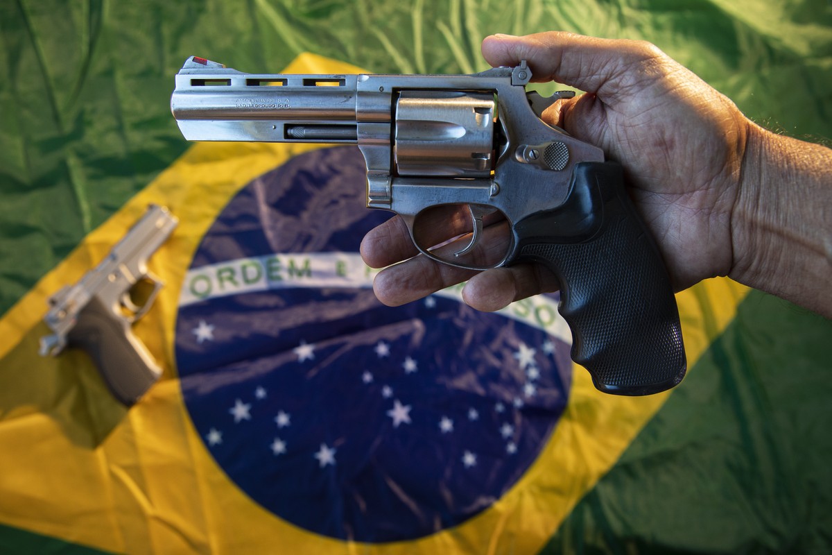 epa10161715 A 65-year-old man poses with a revolver that he uses for his personal security, and Brazilian flags in Brasilia, Brazil, 25 August 2022 (issued 05 September 2022). The number of armed civi ...