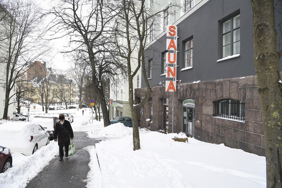 epa09067737 A person walks past a sauna sign in Helsinki, Finland, 11 March 2021. As the pandemic worsens in Finland and specially in Helsinki metropolitan area, many restrictions are tightened. Resta ...