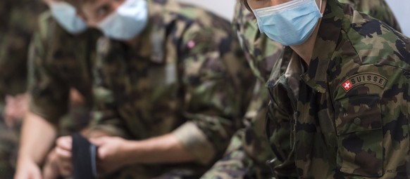 21-year-old Swiss ice hockey player Nico Hischier, center for NHL club New Jersey Devils, right, wears a protective mask after receiving his Swiss army uniform, Tuesday, June 16, 2020 in Wangen and…