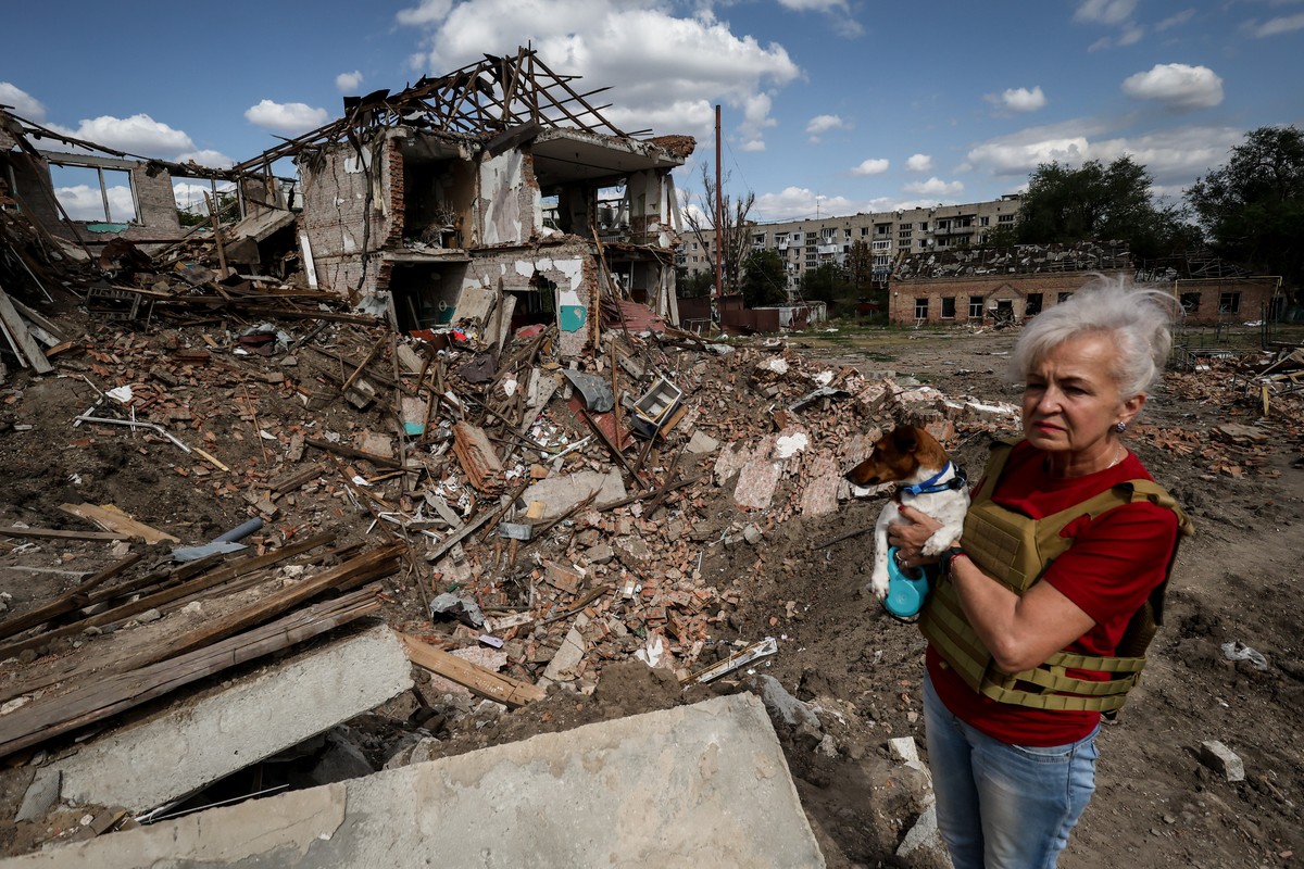 epa10846751 Lubov Jarova holds her dog, Peremoha (victory), as she walks among the rubble of a school in the frontline town of Orikhiv, Zaporizhzhia Oblast, Ukraine, 07 September 2023, amid the Russia ...