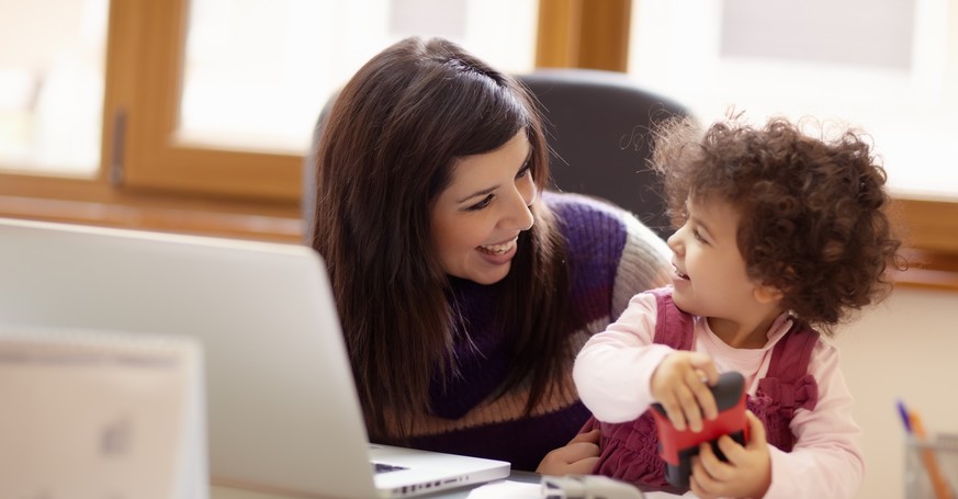 Hier kommt das obligate Stockphoto mit einer glücklichen Mutter und ihrem Kind am Arbeitsplatz. Leider klappt das in der Realität nicht.