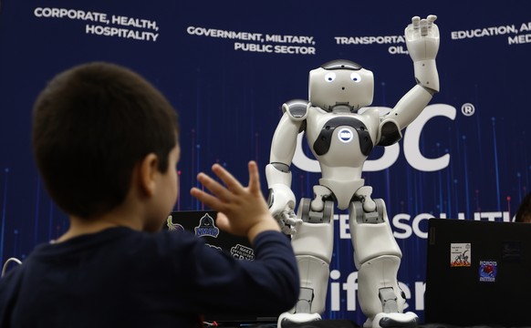 epa12497224 A boy waves to a humanoid robot activated at a technology company stand during the RoboFest 2025 event held on the campus of the Bucharest Polytechnic University, in Bucharest, Romania, 01 ...