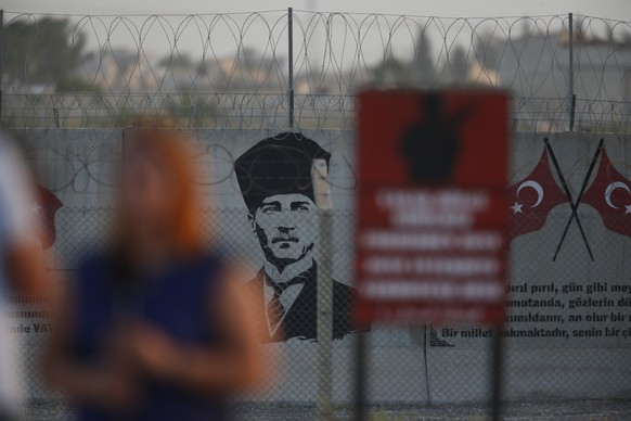 A graffiti of modern Turkey&#039;s founder Mustafa Kemal Ataturk is seen on the Turkish side of the border between Turkey and Syria, as a TV journalist works in Akcakale, Sanliurfa province, southeast ...