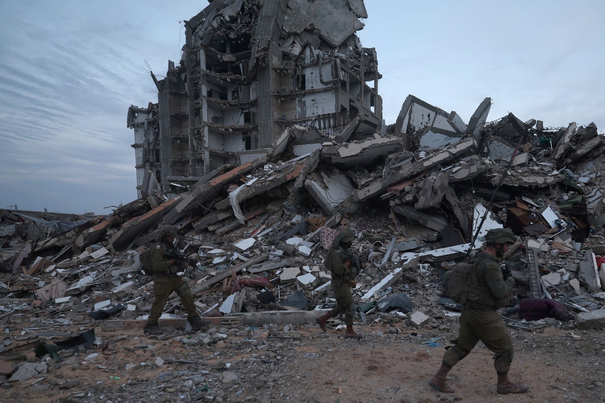 epa11018177 A photo taken while embedded with the Israel Defense Forces (IDF) shows Israeli soldiers walking past the rubble of destroyed buildings in the Palestinian town of Beit Lahia, on the outski ...