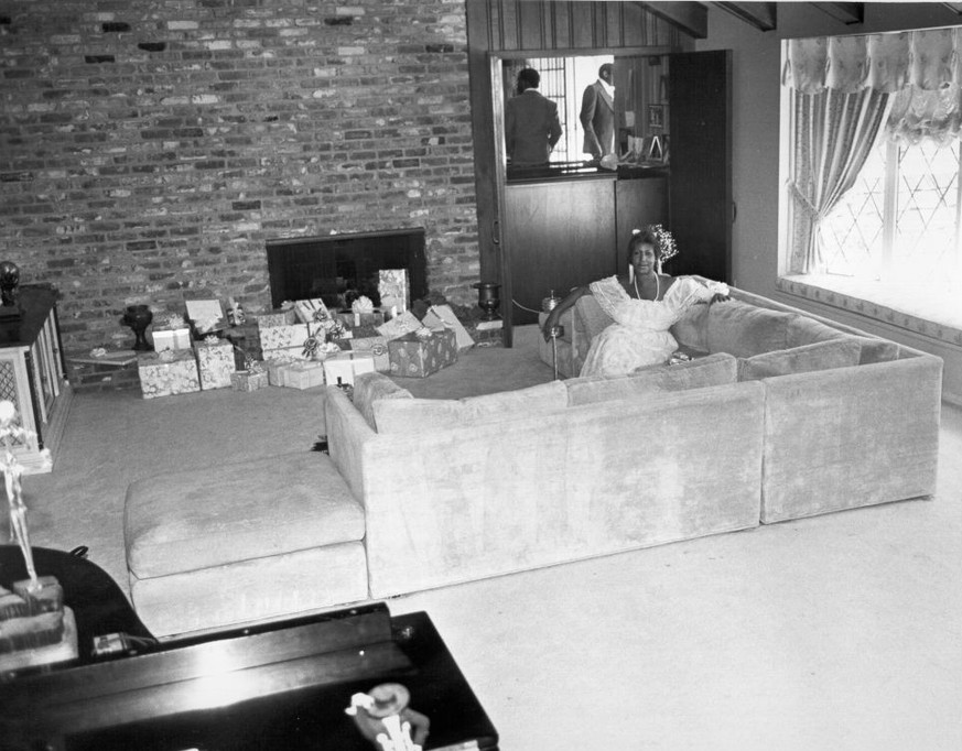 CIRCA 1980: Soul singer Aretha Franklin relaxes at home with Christmas presents by the fireplace in circa 1980. (Photo by Michael Ochs Archives/Getty Images)