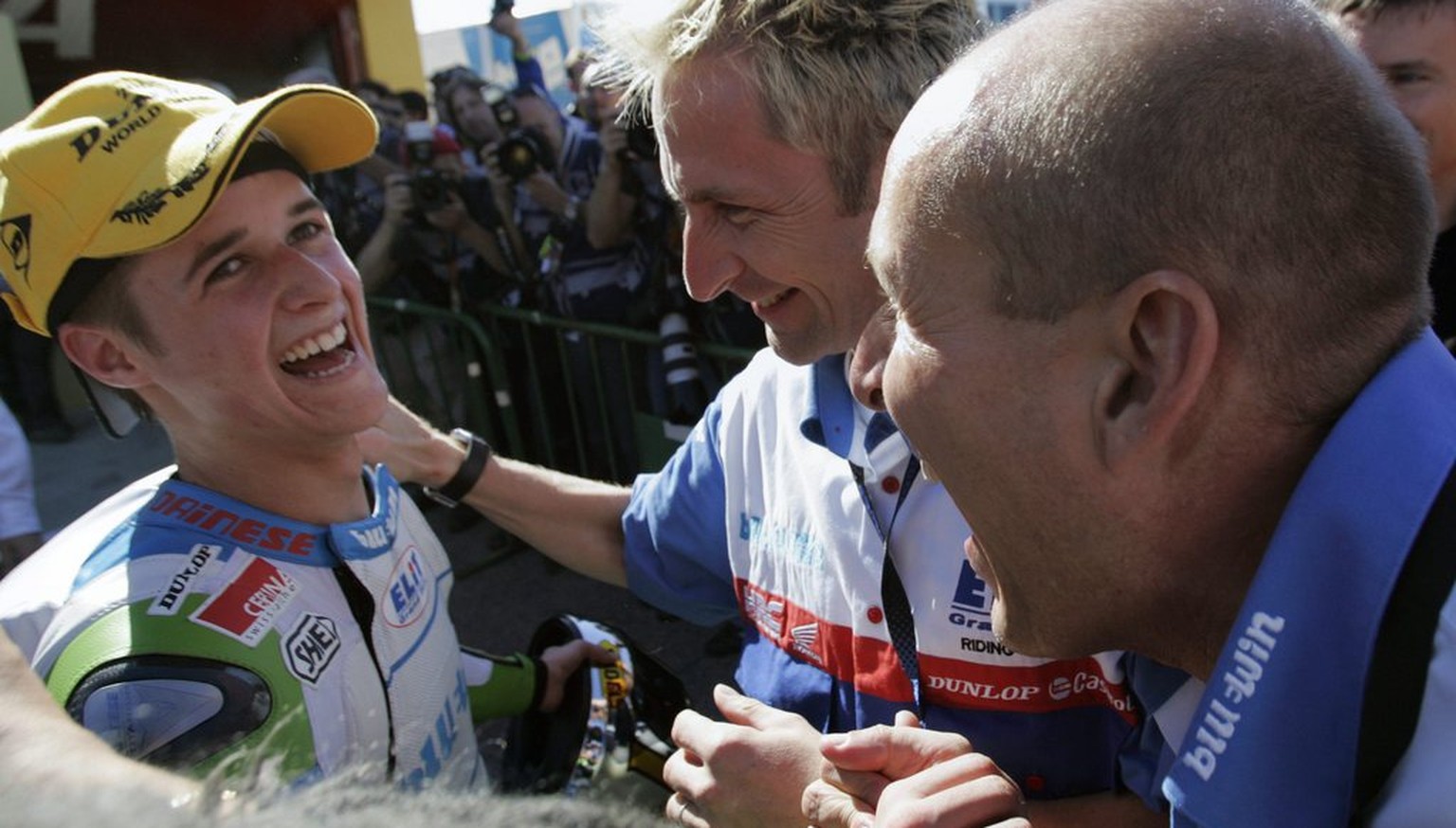 Newly crowned 125cc World Champion, Swiss motorcycle pilot Thomas Luethi from Czech Elit team, left, celebrates with his team owner Daniel Epp from Switzerland, right, and his riding coach Andy Ibbott ...