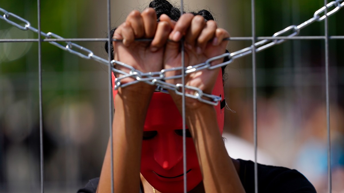 epa06762258 An activist of the association 'Together for Africa' wears masks while playing a slave during the staging of a slave market in front of Brandenburg Gate in Berlin, Germany, 25 Ma ...