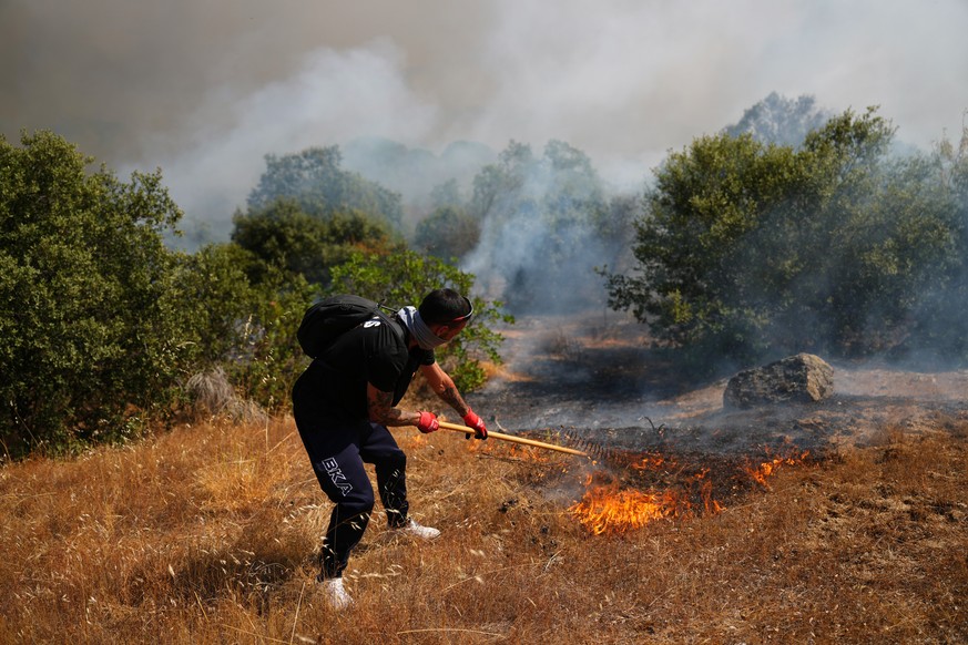 A volunteer uses a rake trying to help stop a wildfire from advancing in San Martin de Valdeiglesias, west of Madrid, Spain, Sunday, July 26, 2026. (AP Photo/Manu Fernandez)
APTOPIX Spain Wildfires