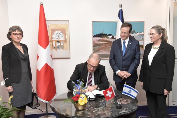Israels Staatspräsident Isaac Herzog (zweiter von rechts) sieht zu, wie sich Bundespräsident Guy Parmelin im Gästebuch verewigt.