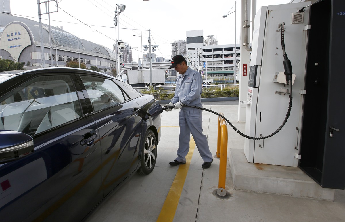 In this photo taken Monday, Nov. 17, 2014, a fuel cell charge station worker demonstrates how to charge hydrogen to a Toyota Motor Corp.'s new fuel cell vehicle Mirai at a charge station near Toy ...
