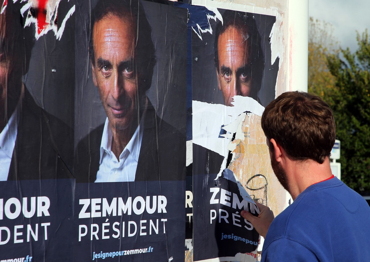 A man tears off posters showing hard-right political talk-show star Eric Zemmour in Biarritz, southwestern France, Tuesday, Oct. 26, 2021. Provocative anti-immigration commentator Eric Zemmour is draw ...