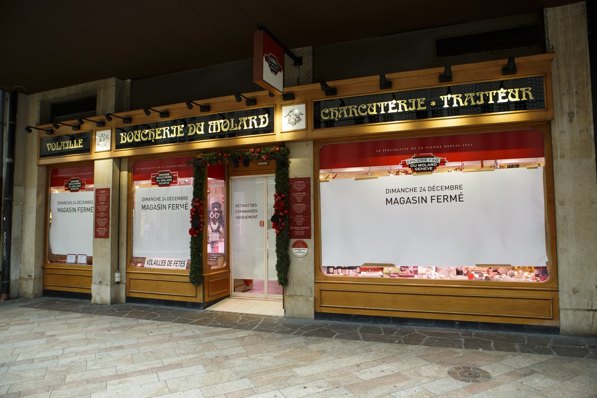 Les vitrines du magasin de la boucherie du Molard sont couvertes de nappes de papier avec les inscriptions "Dimanche 24 decembre magasin ferme" "Retrait des commandes uniquement",  ...