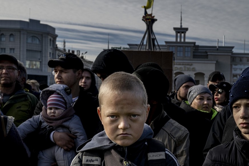 On November 11, 2022, Ukrainian troops liberated Kherson from Russian occupation.  In a busy square, the crowd falls silent as President Zelensky gives a speech.  Glib, a 13-year-old boy, listens...